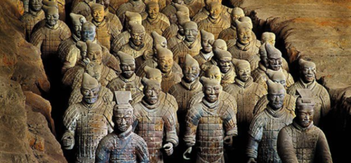 Many lifelike terra-cotta soldiers in a cave trench inside a tomb.