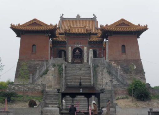 His tomb, there are tall staircases leading up to it and the building has red walls and a gold colored tiled roof.