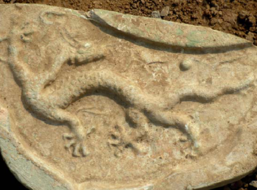 Piece of the tiled roof, the carving depicts part of an animal.